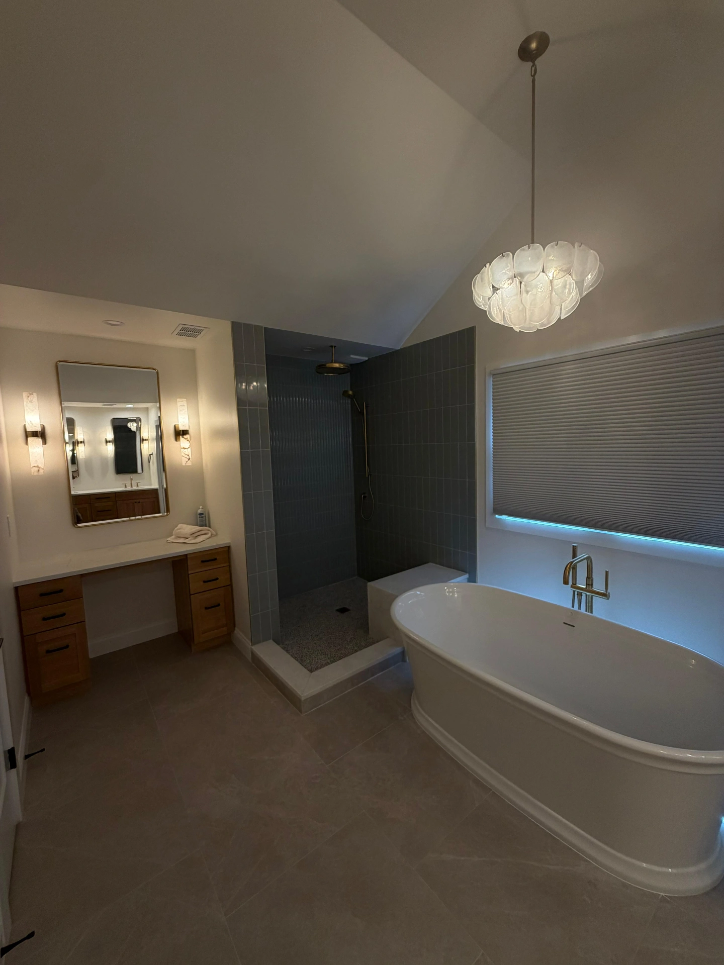 Bathroom with an open tiled shower, freestanding tub, and double vanity lighting