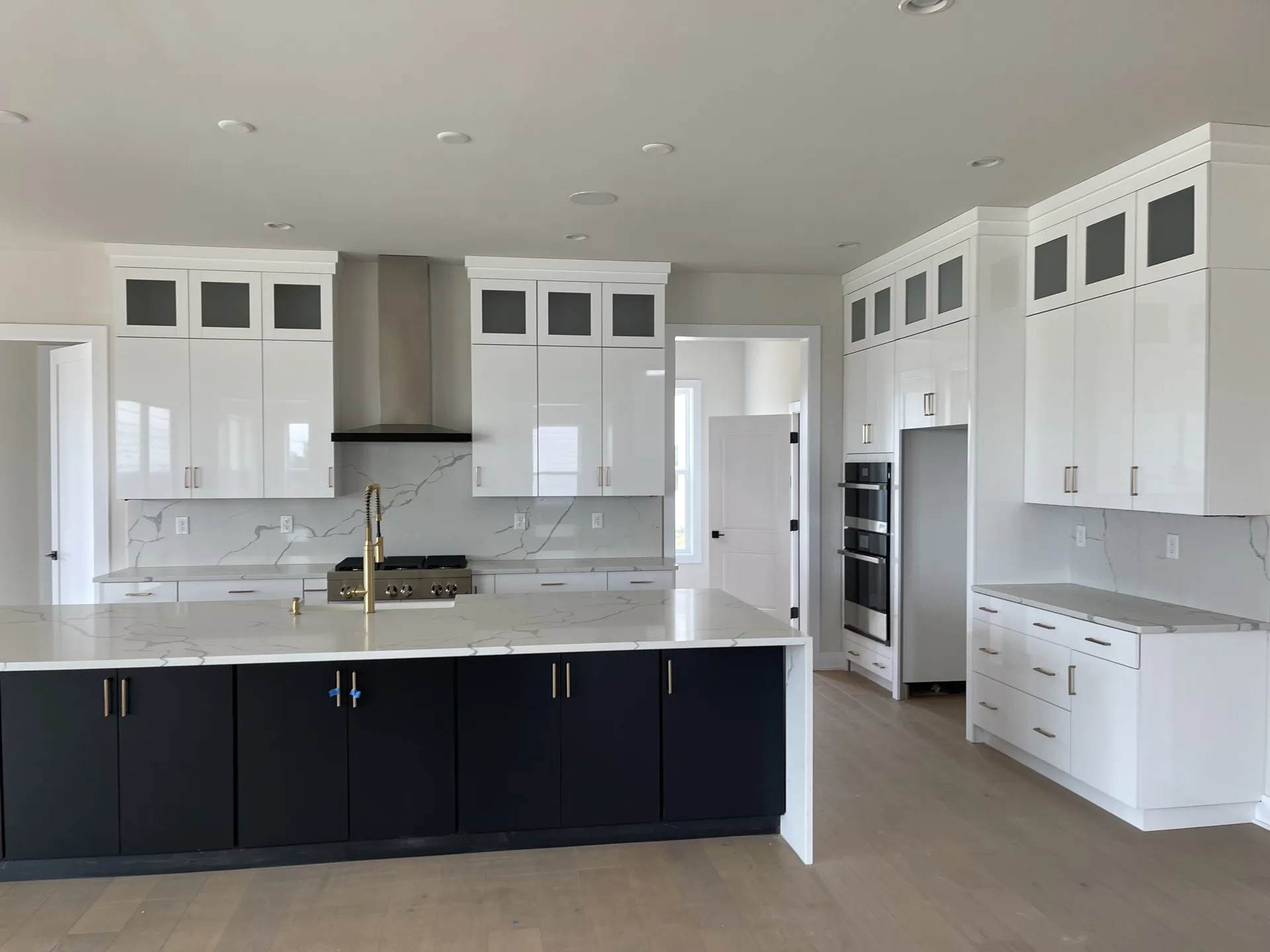Finished white kitchen with a dark navy island, waterfall counters, and brass faucet by A1 Brothers