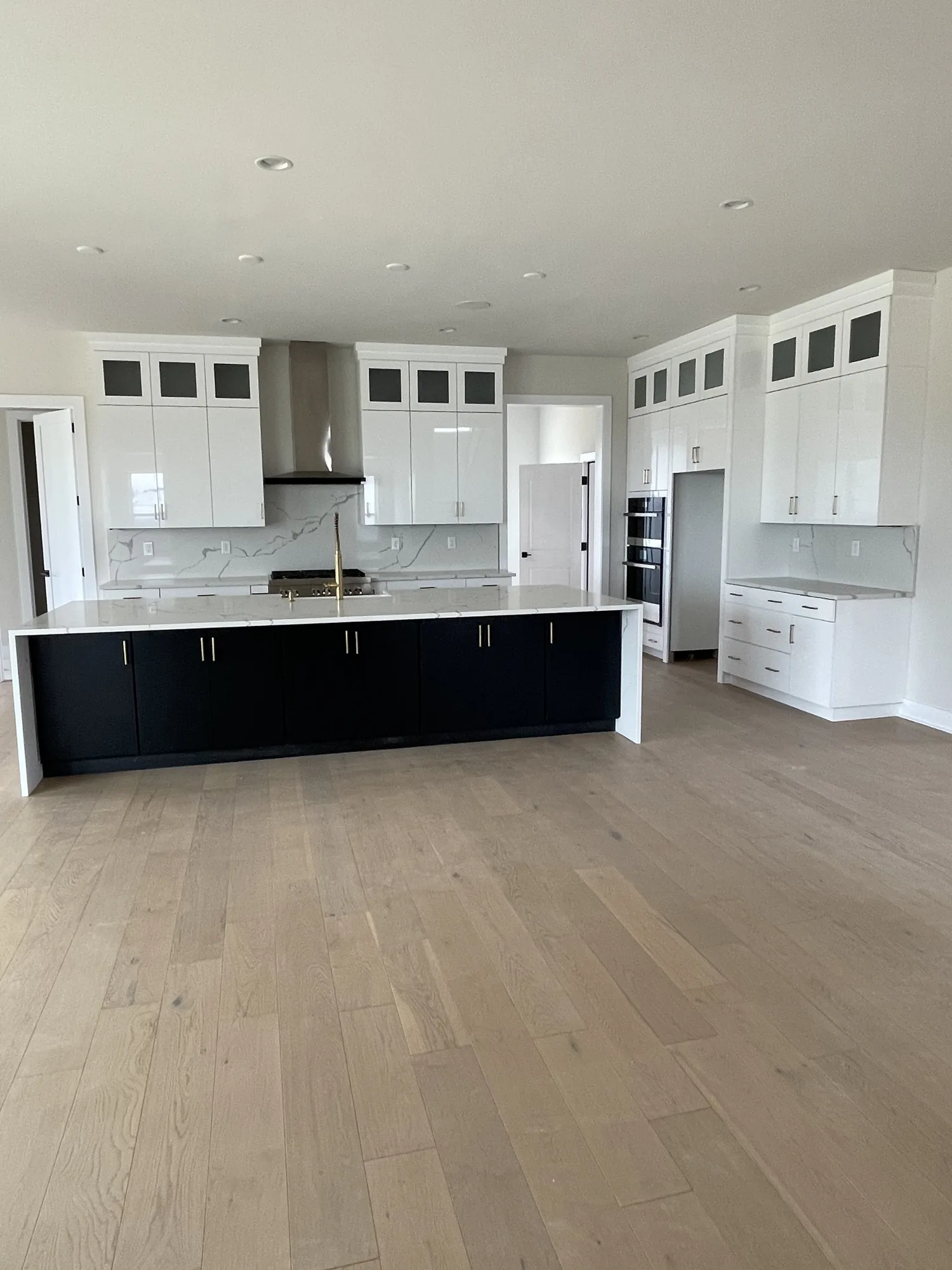 Finished white kitchen with a dark navy island, waterfall counters, and brass faucet